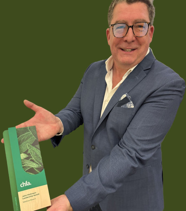 Man in a suit holding a green chia product packaging in an indoor setting
